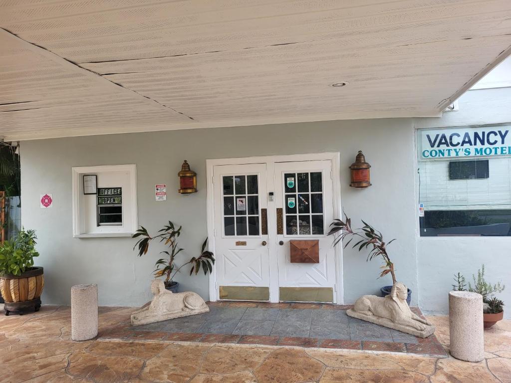 uma porta da frente de um edifício branco com plantas em Conty's Motel em Naples