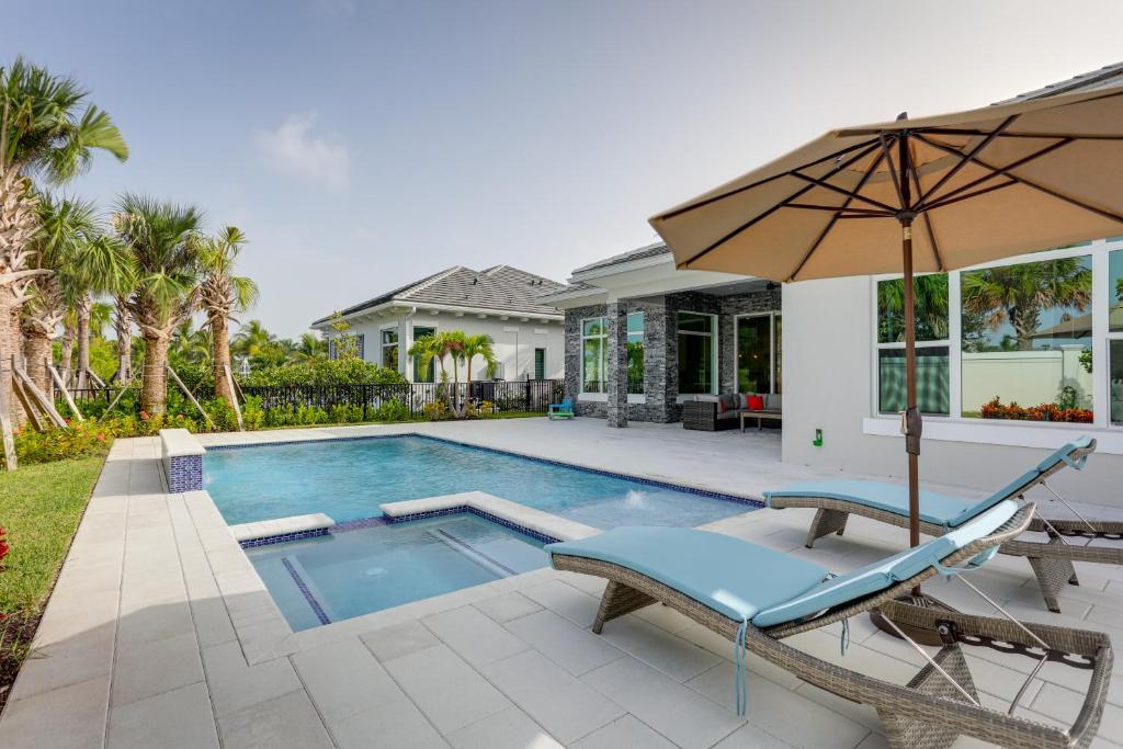 une maison avec une piscine et un parasol dans l'établissement Luxe Palm Beach Gardens Home with Private Pool and Spa, à Palm Beach Gardens