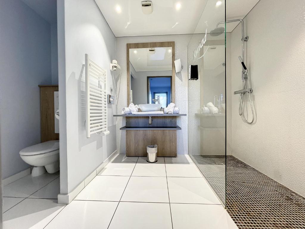 a bathroom with a shower and a toilet and a sink at Kyriad Prestige Residence & Spa Cabourg-Dives-sur-Mer in Dives-sur-Mer