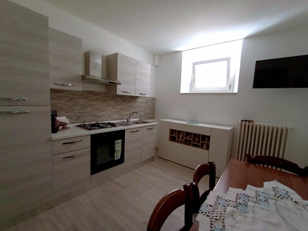 cocina con armarios blancos, mesa y ventana en pesa apartment B&B, en Ascoli Piceno