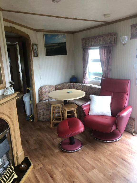 a living room with a red chair and a table at Màire’s Mobile Home in Falcarragh
