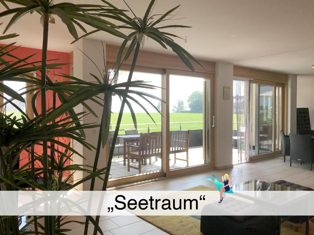 uma sala de estar com portas de vidro deslizantes e plantas em Ferienwohnung Seetraum - Hoch über dem See, großzügig mit großem Balkon em Kressbronn am Bodensee