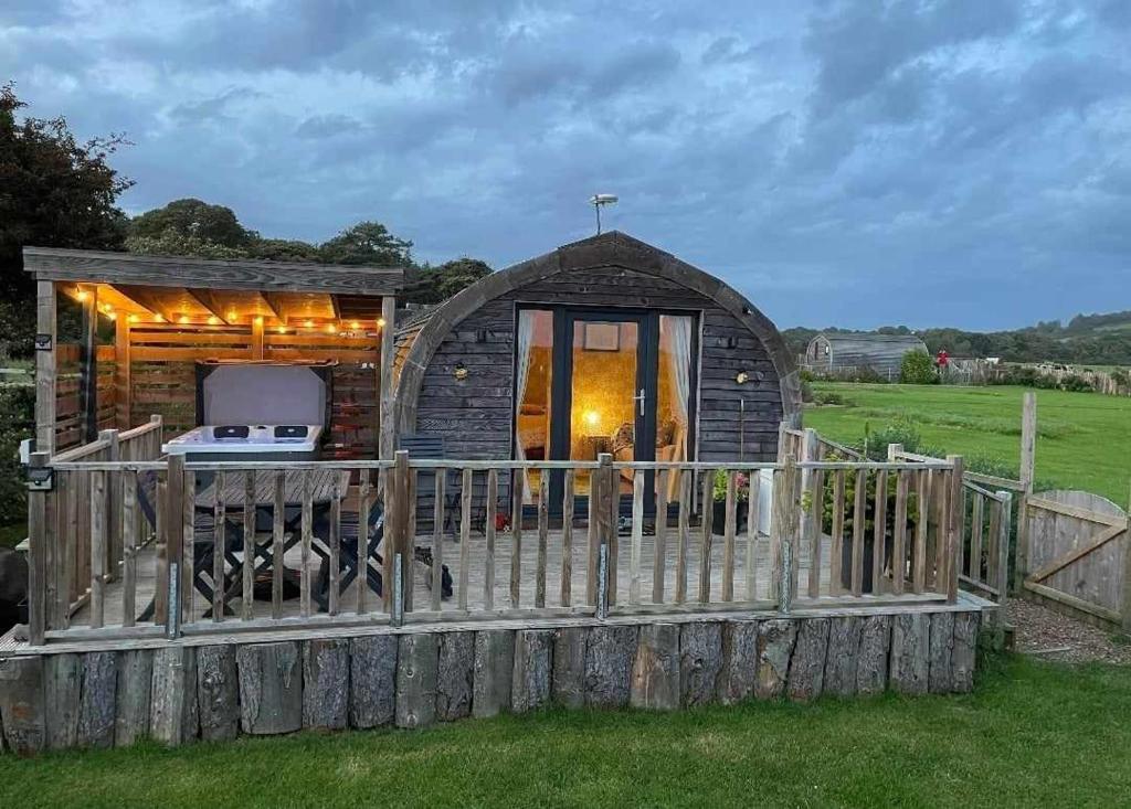 una pequeña cabaña en un campo con una valla en Beautiful couples retreat with hot tub, central heating and views- The Bee Hive by Get Better Getaways, en Glenluce