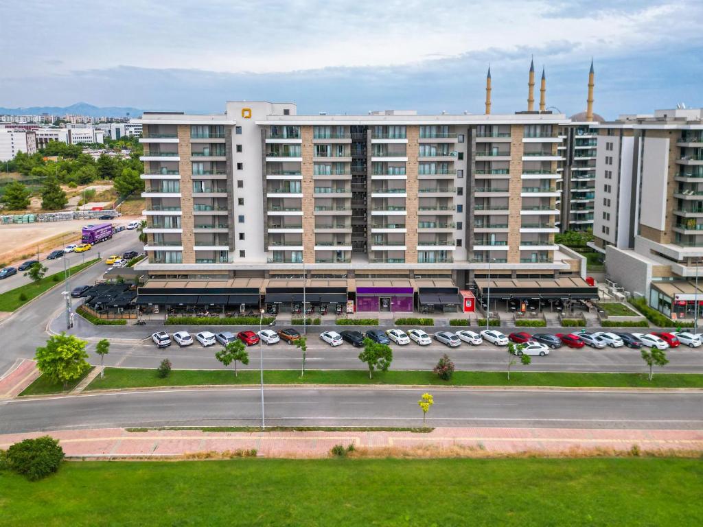 een groot gebouw met auto's geparkeerd op een parkeerplaats bij Casamax Suites in Antalya