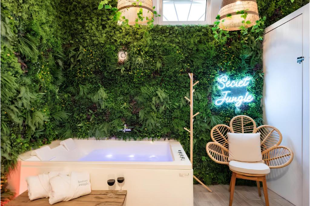 ein Badezimmer mit einer grünen Wand mit einer Badewanne und Stühlen in der Unterkunft Secret Jungle Bordeaux Chartrons - Hyper-Centre Jacuzzi Bain Balnéo & Home cinéma in Bordeaux