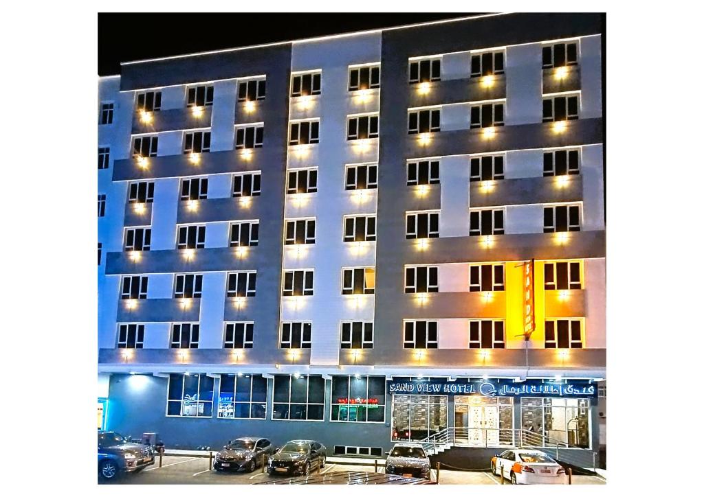 a building with cars parked in front of it at Hotel Sand View in Bawshar