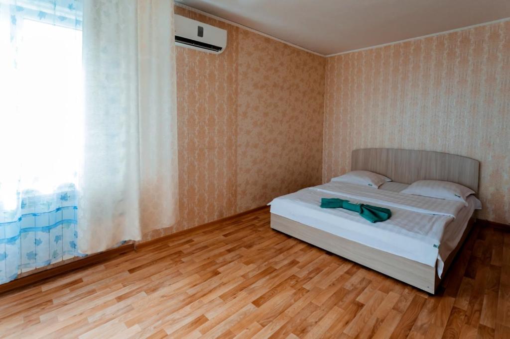 1 dormitorio con cama, ventana y suelo de madera en Варна, en Petropavlovsk