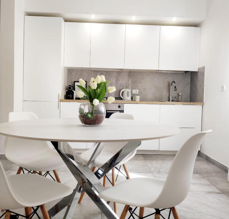 a white kitchen with a table and white chairs at Dibbio's house in Guidonia