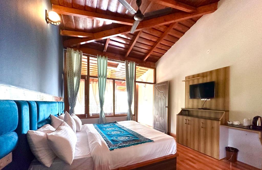 a bedroom with a bed with a blue headboard and a television at The little nest Home Stay in Bhīm Tāl