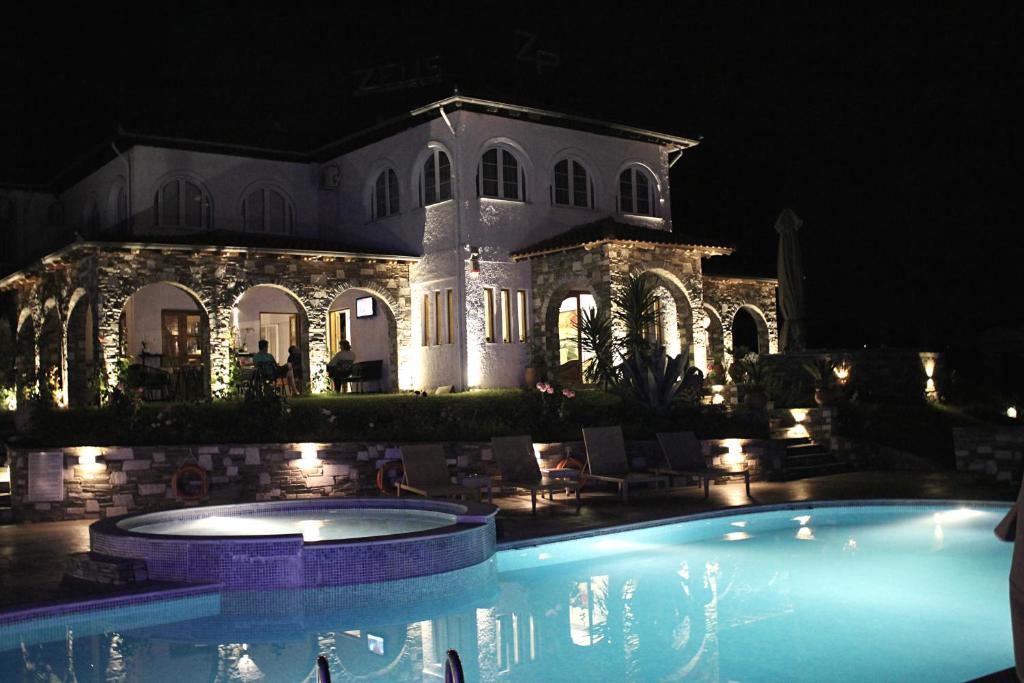 a large house with a swimming pool at night at Zeus Hotel in Platamonas