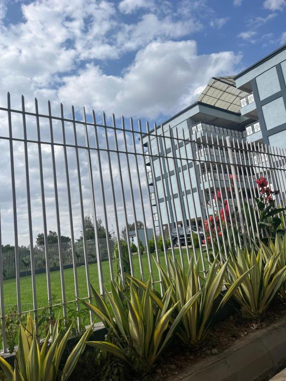 a fence in front of a building with plants at Koselig California in Nanyuki