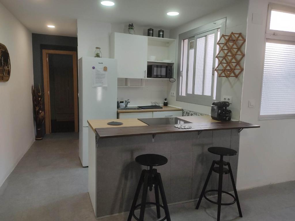 a kitchen with a counter and two bar stools at Luminoso apartamento en centro del pueblo con Wifi y A' A' in Sagunto