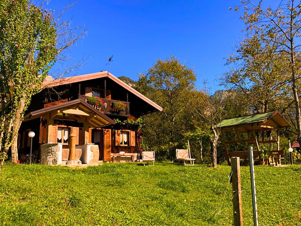 uma casa de madeira com um alpendre e um banco na relva em Chalet Relax Tra Le Vigne em Forni di Sotto