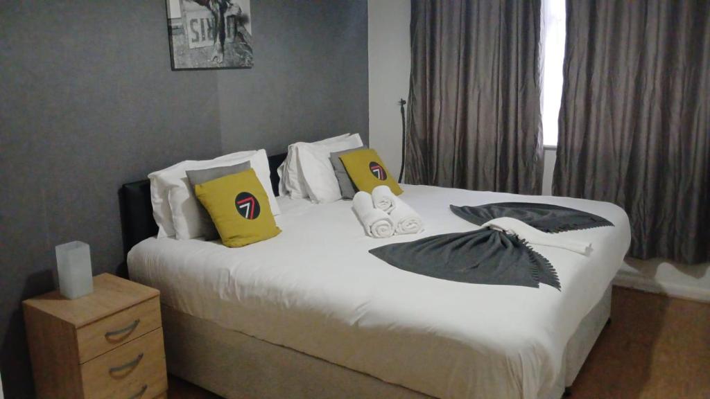 a bedroom with a large bed with yellow and black pillows at Seven Suites - Beautiful 2-Bed Apartment with Parking in Watford Central in Watford