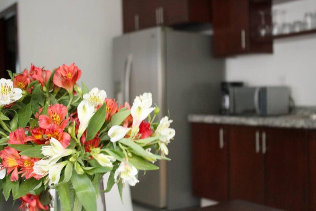 un jarrón de flores en una cocina con nevera en Hermoso departamento con una excelente ubicación, en Guadalajara