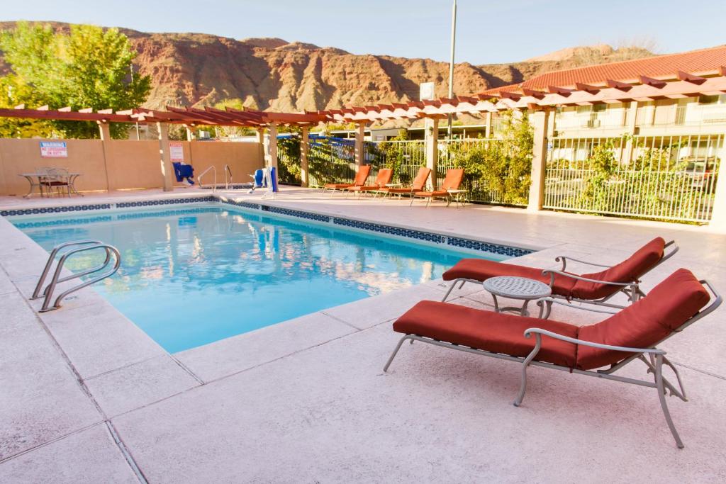 a swimming pool with two red lounge chairs next to it at Hotel Moab Downtown in Moab