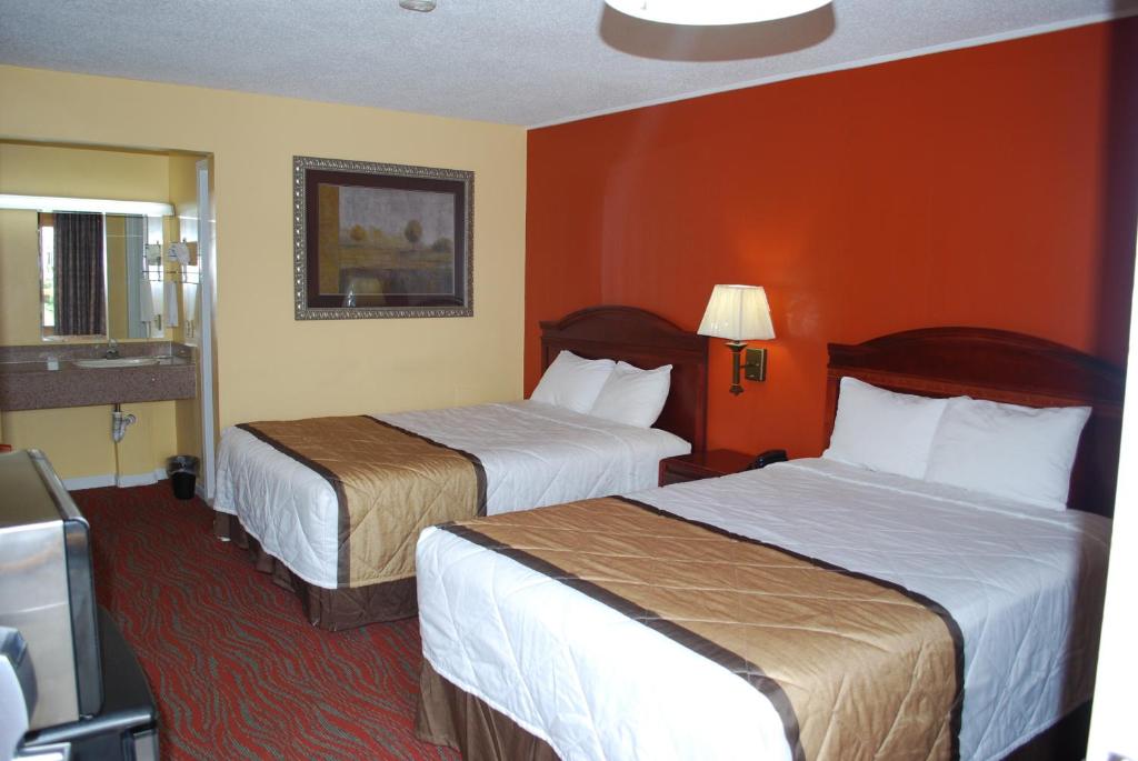 two beds in a hotel room with orange walls at Duffys Motel - Calhoun in Calhoun