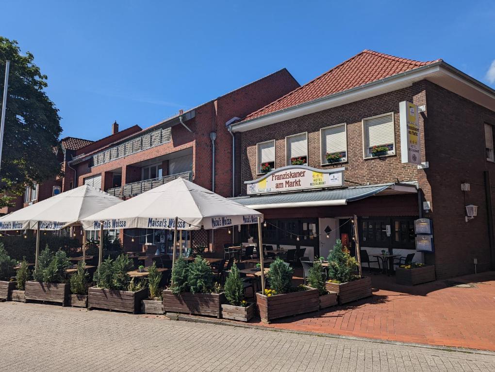 a building with tables and umbrellas on a street at Franziskaner am Markt in Löningen