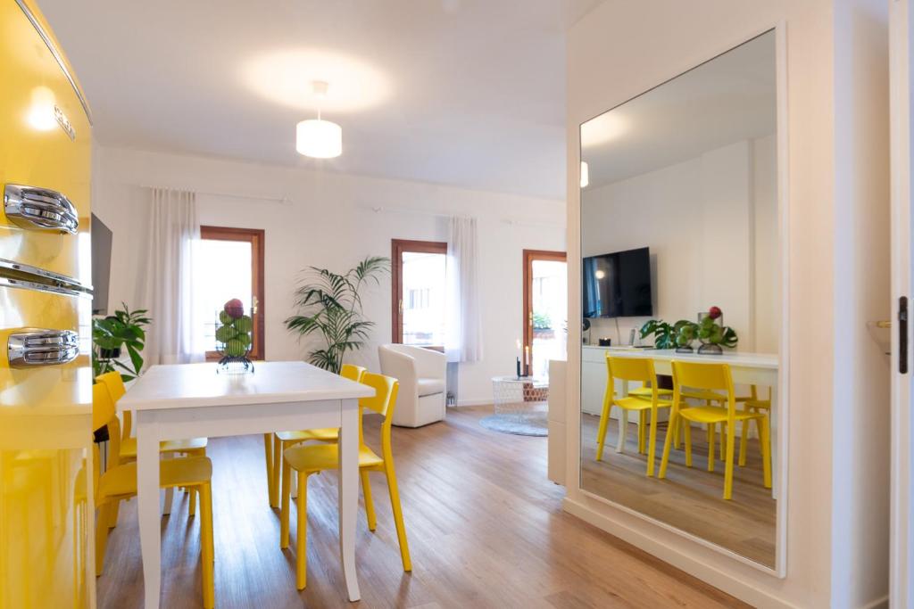 Giustiniani Apartments في تريفيزو: غرفة طعام مع طاولة وكراسي صفراء