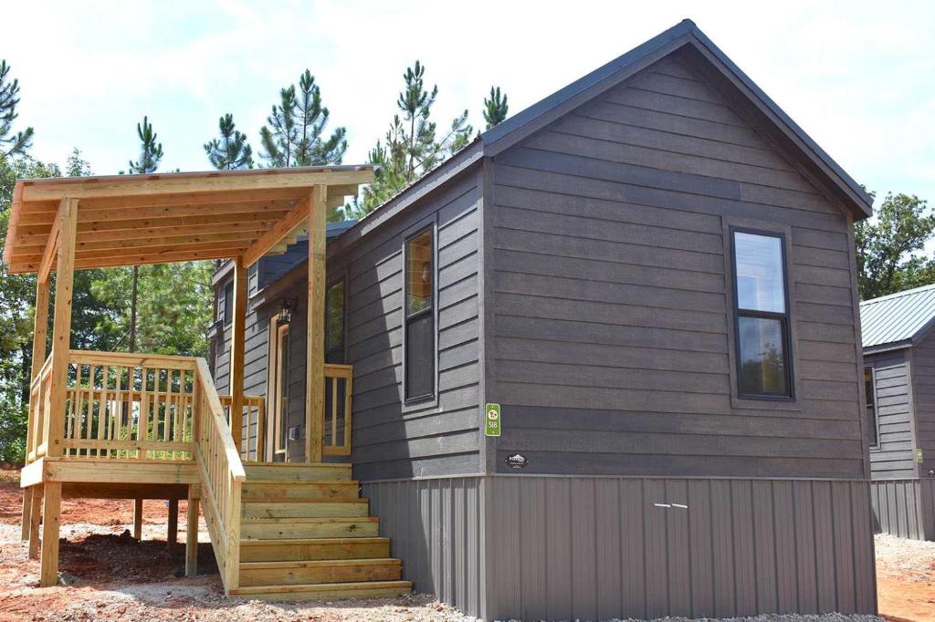a tiny house with a staircase and a deck at Jellystone Park Tyler in Tyler