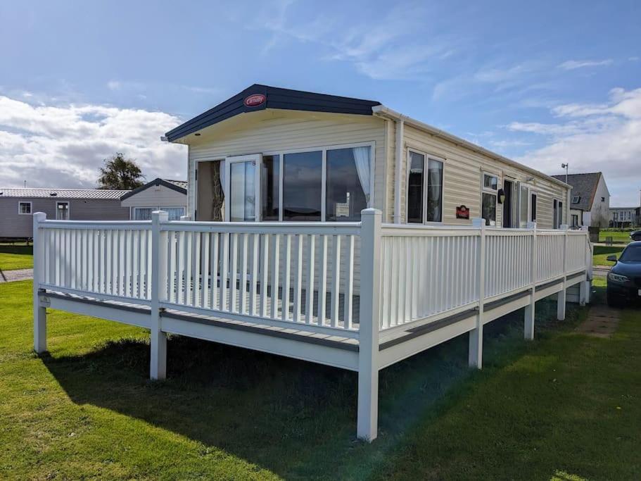 Casa móvil con barandilla blanca y porche en Beautiful Pet Friendly Southerness Caravan With Sea View & Decking Area en Mainsriddle