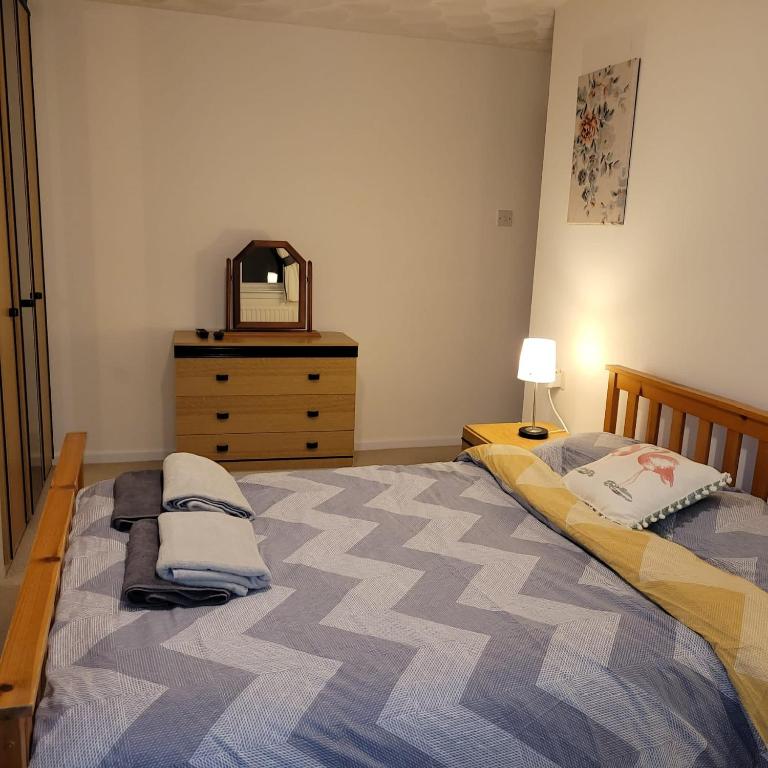 a bedroom with a bed and a dresser with a mirror at EEJs Cozy 2-Bedroom Apartment in Nailsea in Nailsea