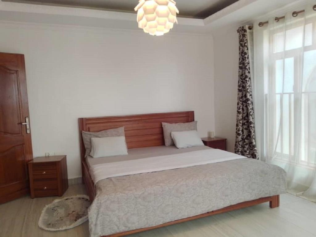 a bedroom with a large bed and a chandelier at Kagarama Residential House: in Kigali