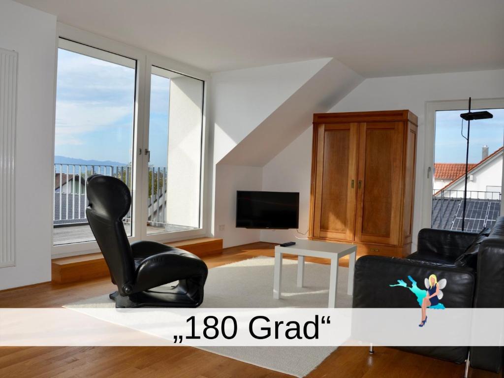 a living room with a black chair and a tv at Ferienwohnung 180 Grad in Wasserburg am Bodensee