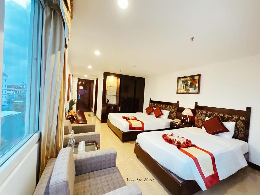 a hotel room with two beds and a large window at Vina Spa Hotel in Hue