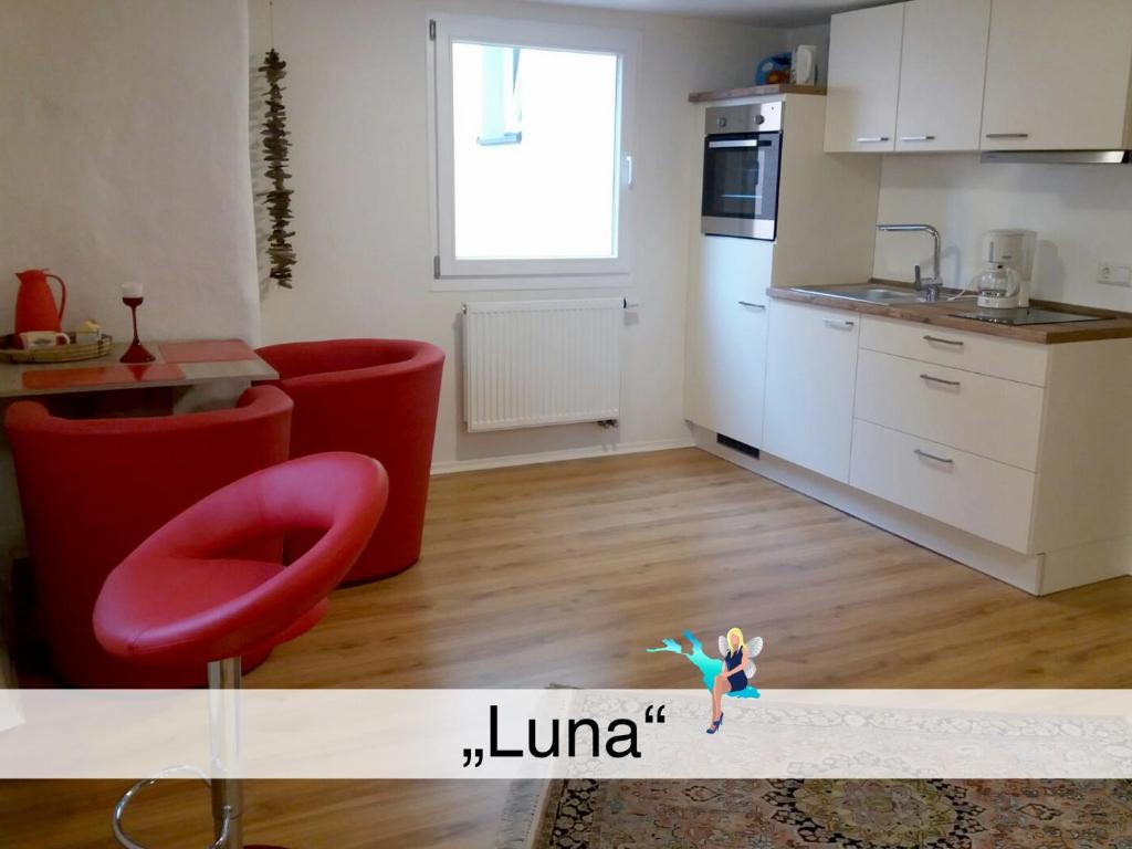 ein Wohnzimmer mit einer Küche und einem roten Stuhl in der Unterkunft Ferienwohnung Luna in Lindau