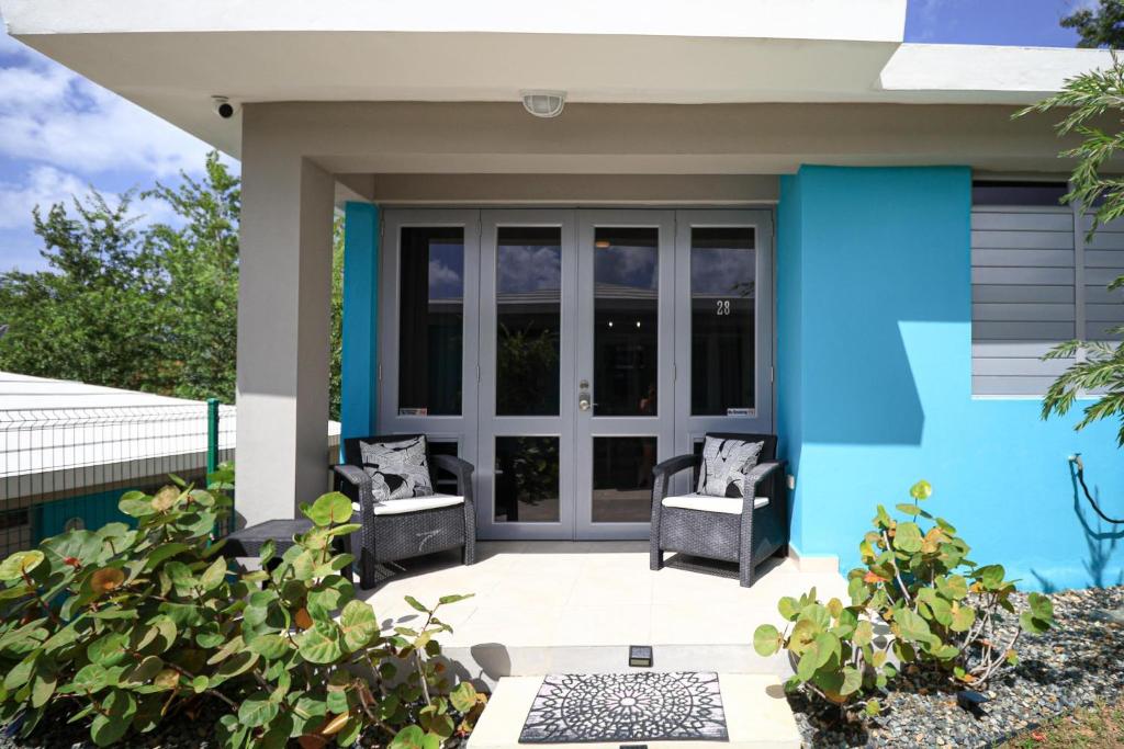 una casa azul con 2 sillas en un patio en Casa Arrecife 28, en Cabo Rojo
