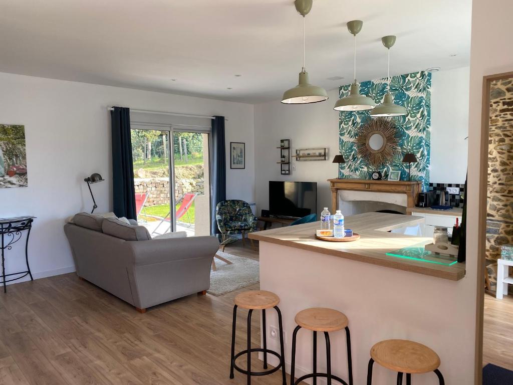 a kitchen and living room with a counter and stools at Gîte P&M à la campagne in Bruc-sur-Aff