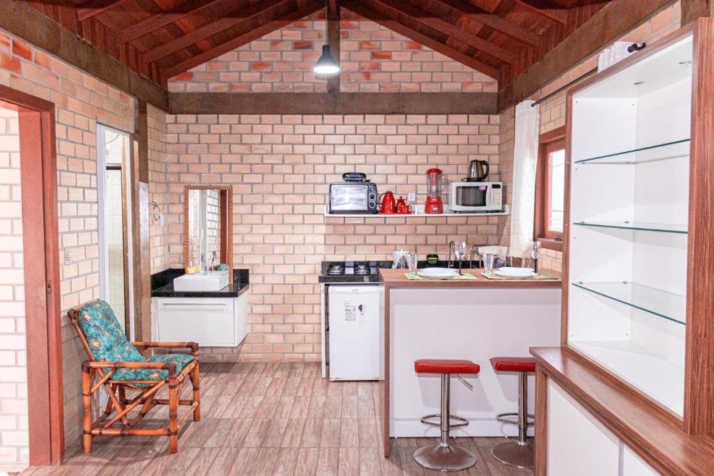 a kitchen with a counter and chairs in a room at Bangalo da santa in Guarda do Embaú