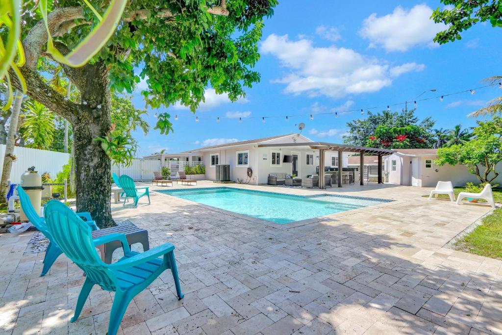 una piscina con sillas, un árbol y una casa en The Gardens - Luxury Retreat with Pool & Game Room, en Miami Gardens