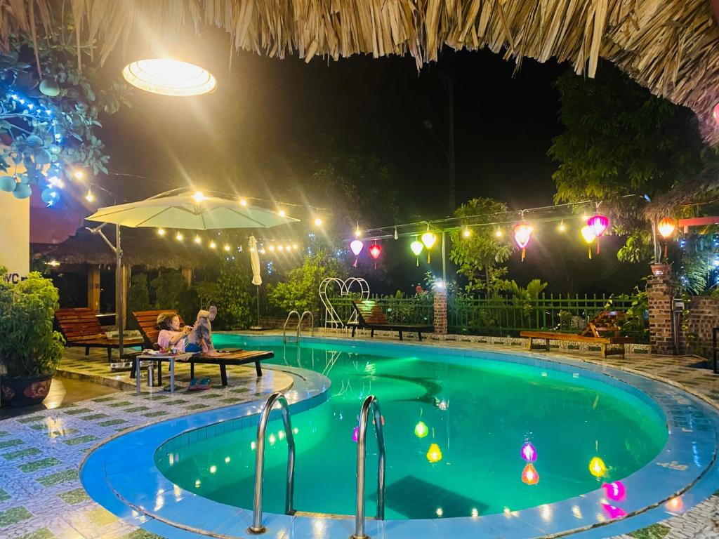 una piscina por la noche con gente sentada alrededor de una mesa en Tam Coc Little river Bungalow en Ninh Binh