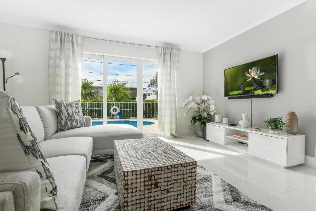 Una sala de estar blanca con un sofá y un televisor. en 10 mins from Pompano Beach! With pool access, en Pompano Beach