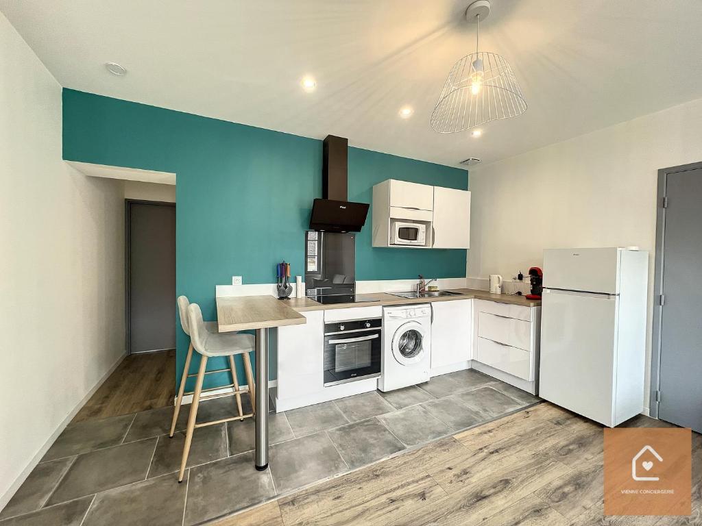 uma cozinha com electrodomésticos brancos e uma parede azul em Le blue Lagoon - 2 pers - Arrivée Autonome em Châtellerault
