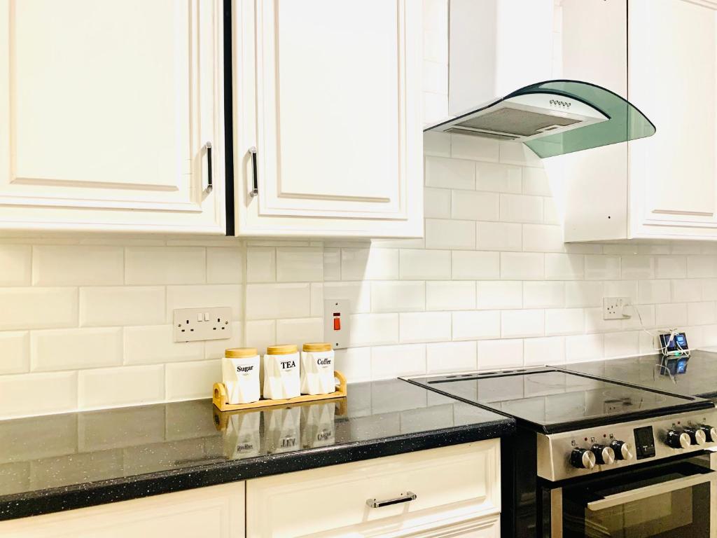 a kitchen with white cabinets and a black counter top at Cosy 2 bedroom apartment in Swiss Cottage. in London