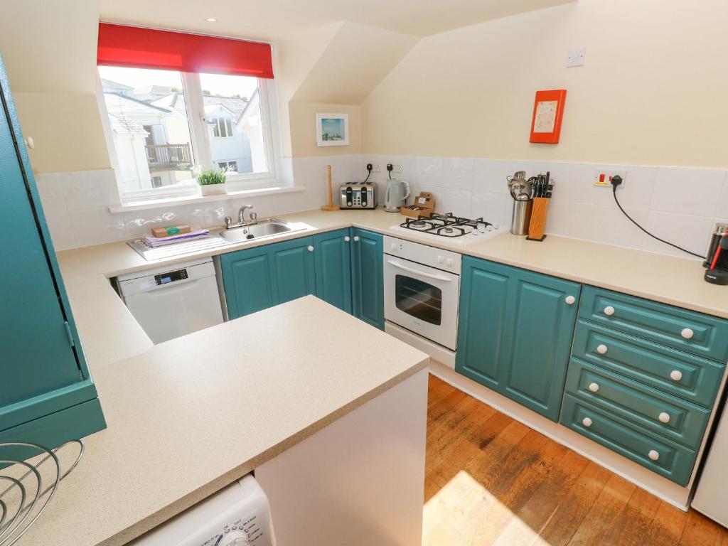 a kitchen with green cabinets and a white counter top at The Beach House in Newquay