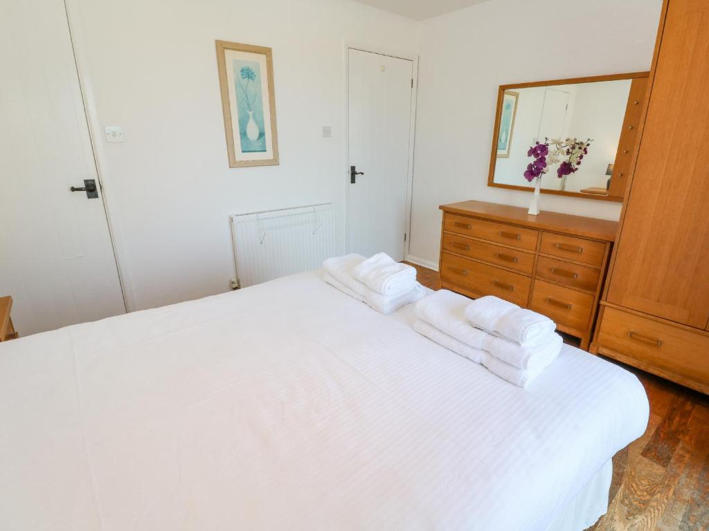 a bedroom with a white bed with towels on it at The Beach House in Newquay