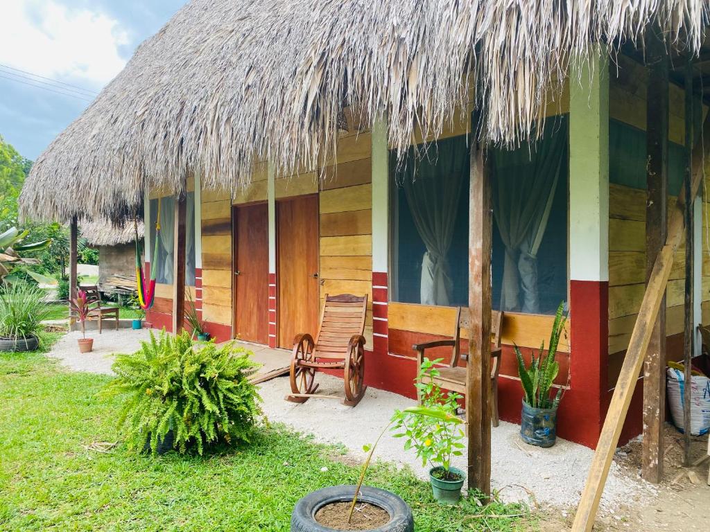 a house with a straw roof and a chair in front at Topche, Centro Ecoturístico in Lacanjá