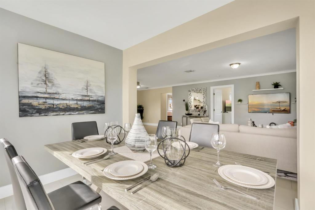 Un comedor con una mesa con platos y copas de vino. en Bright Pompano Beach with pool access, en Pompano Beach