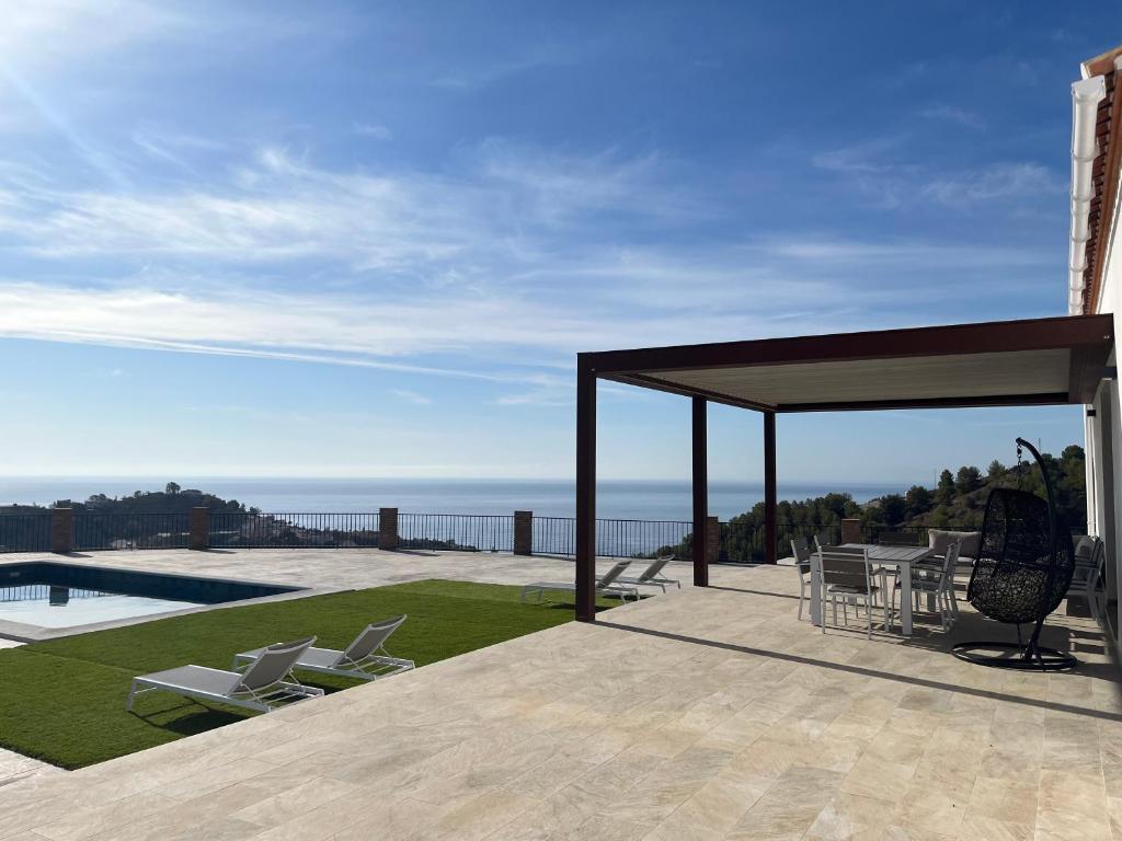 a pavilion with chairs and a view of the ocean at Vivienda en Granada, Cortijo Balcón Cotobro, Almuñécar, Casa con piscina y vistas increíbles in Granada