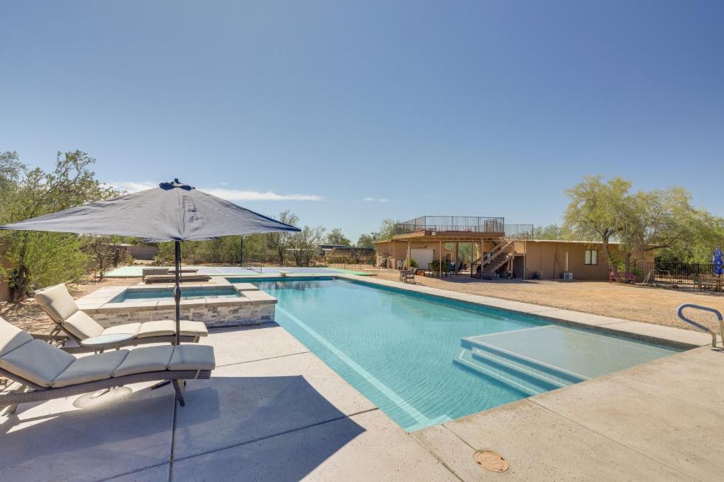 ein Pool mit einem Sonnenschirm, 2 Stühlen und einem Sonnenschirm in der Unterkunft Oro Valley Retreat with Pool, Spa and Rooftop Views! in Oro Valley