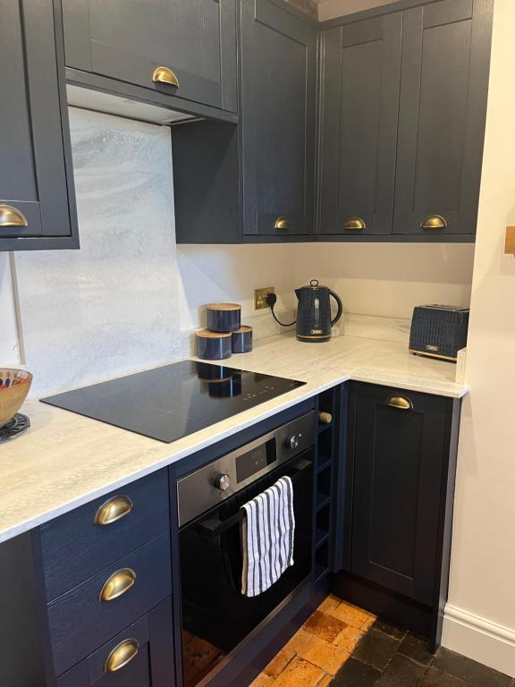 a kitchen with black cabinets and a black dishwasher at 2 Bed Cottage, Houghton on the Hill, Leicestershire in Houghton on the Hill