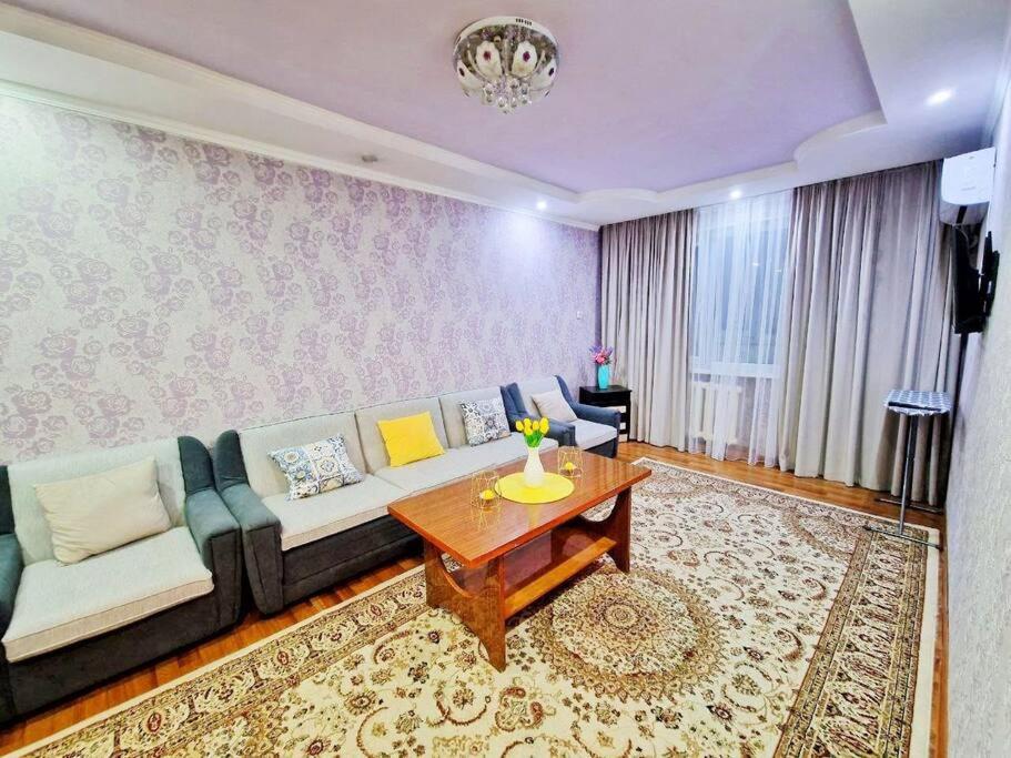 ein Wohnzimmer mit einem Sofa und einem Tisch in der Unterkunft 2-х комнатная квартира рядом с Толе би in Taras