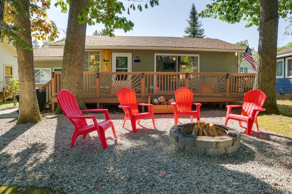 a group of red chairs sitting around a fire pit at Higgins Lake Cottage with Private Fire Pit and Grill! in Roscommon