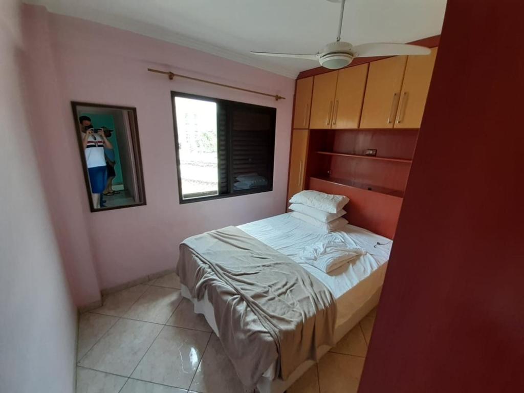 - une chambre avec un lit et une personne prenant une photo dans l'établissement Apartamento inteiro na Enseada, à Guarujá