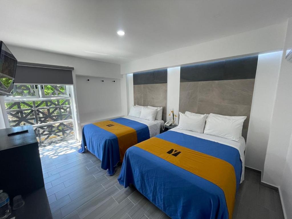 a bedroom with two beds with blue and yellow at Hotel GALENO in Veracruz