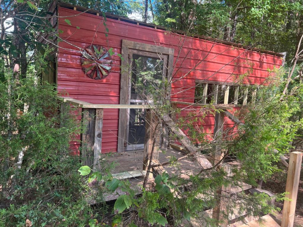 ein altes rotes Haus mit einer Tür im Wald in der Unterkunft The Happy Place In The Trees in Lake Murray Shores